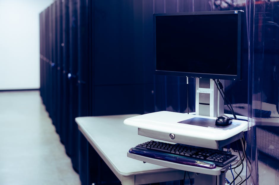 Contemporary computer with black screen placed near server racks in data center.